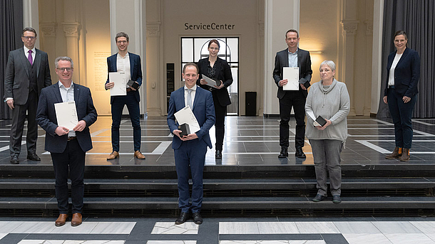 Im Lichthof stehen LUH-Präsident Prof. Dr. Volker Epping und die Vizepräsidentin für Lehre und Studium der LUH, Prof. Dr. Julia Gillen mit den sechs Lehrenden, die ausgezeichnet wurden.