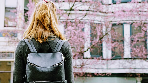 Frau mit Rucksack sieht zu Gebäude