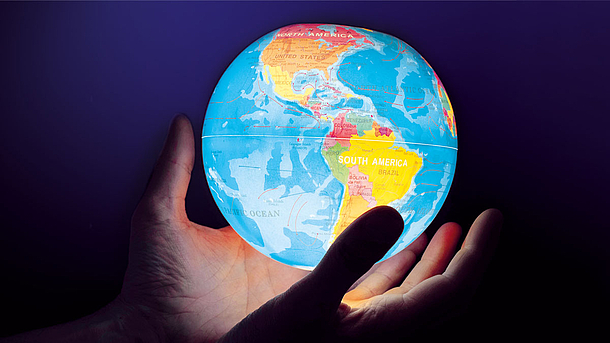 Eine Person hält einen leuchtenden Globus in den Händen