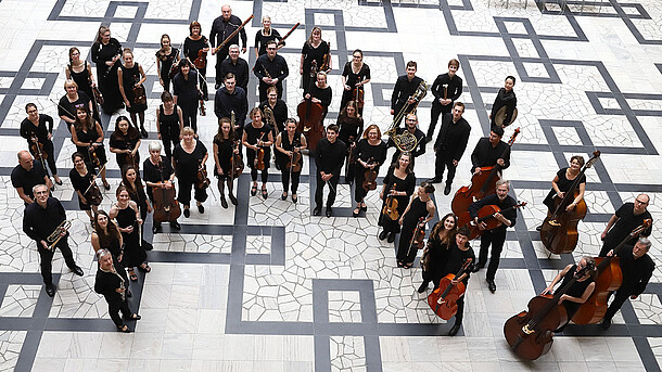 Mitglieder des Orchesters collegium musicum der LUH stehen mit ihren Instrumenten im Lichthof des Welfenschlosses