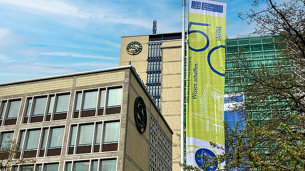 View of the Faculty of Economics building with a flag bearing the inscription "50 years. Understanding economics. Creating knowledge"