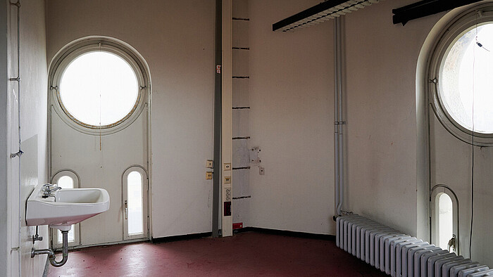 Leer stehendes Turmzimmer, ein Waschbecken links, zwei runde Fenster