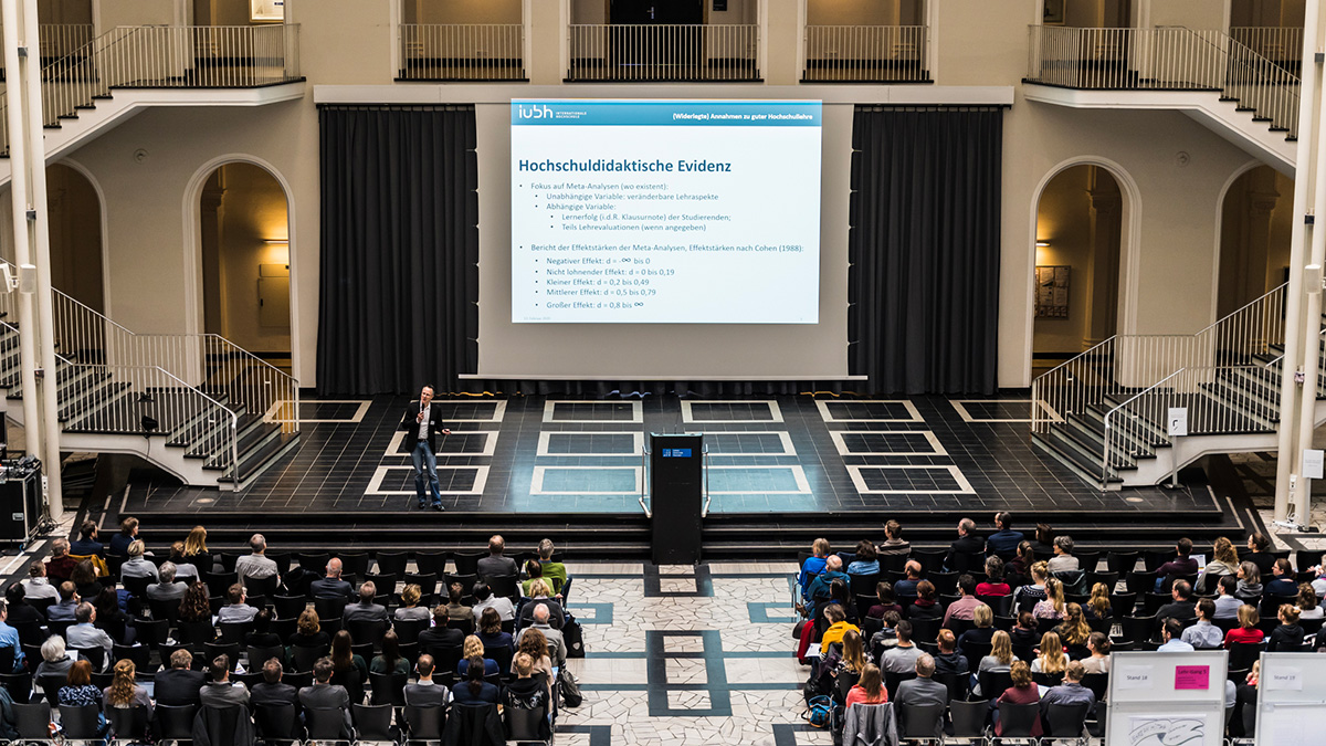 Viele Personen folgen im Lichthof einem Vortrag.