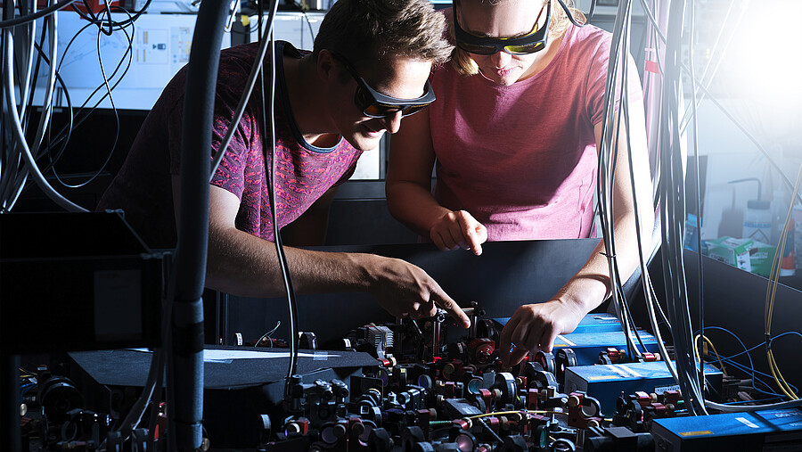 Two people work on a machine.