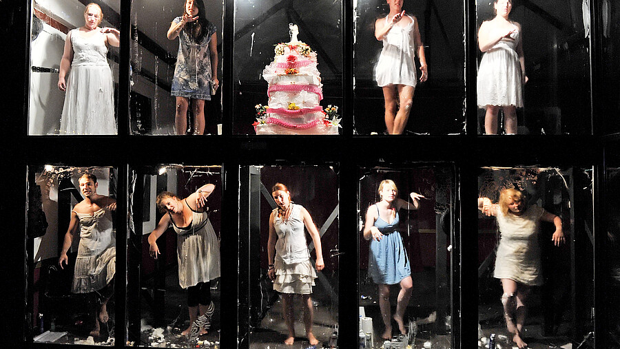 Different people stand in different positions in glass boxes.