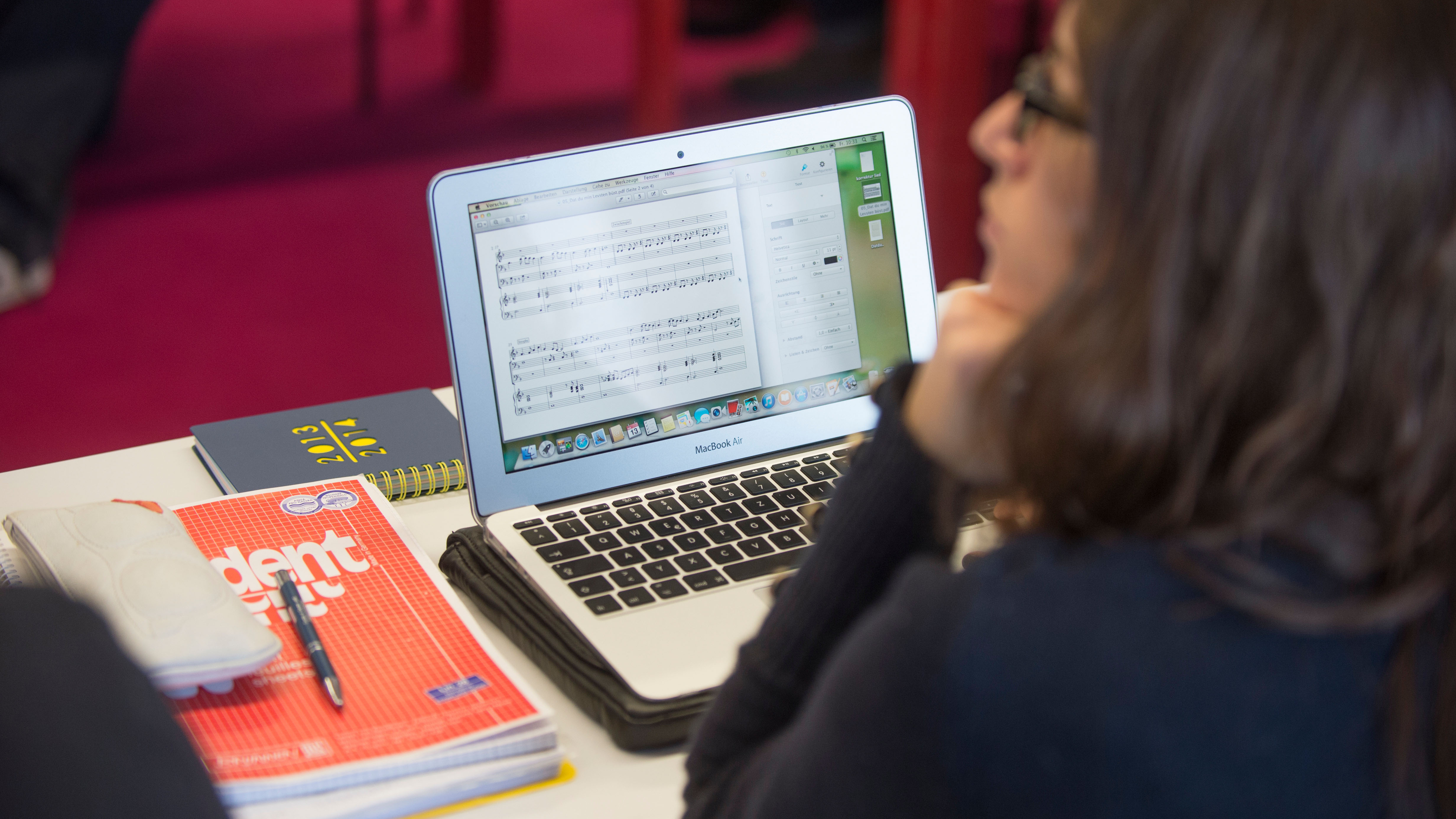 A person works on a laptop with sheet music on it.